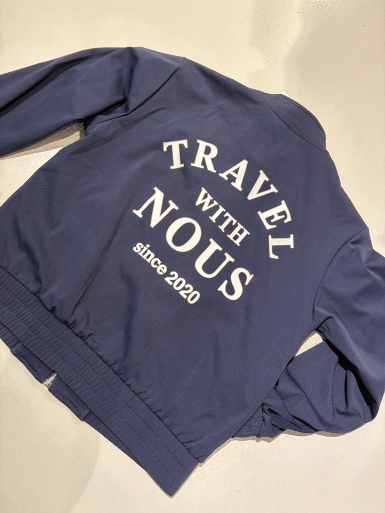 Blauw NOUS kledingstuk met Travel with NOUS opdruk
